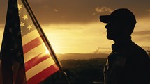 Silhouette of Military Salute of soldier for memorial day against flag at sunset
