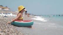 Summer vacation concept. Happy child in the sea. Young girl playing in the wave in beach. Young lady sitting in foam of sea.