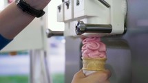a man putting ice cream in an ice cream cone 
