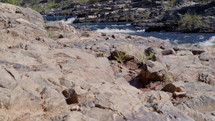Dolly shot of mountain river rapids surrounded by colorful rocks and vegetation. 
