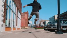 man jumping up on a sidewalk 