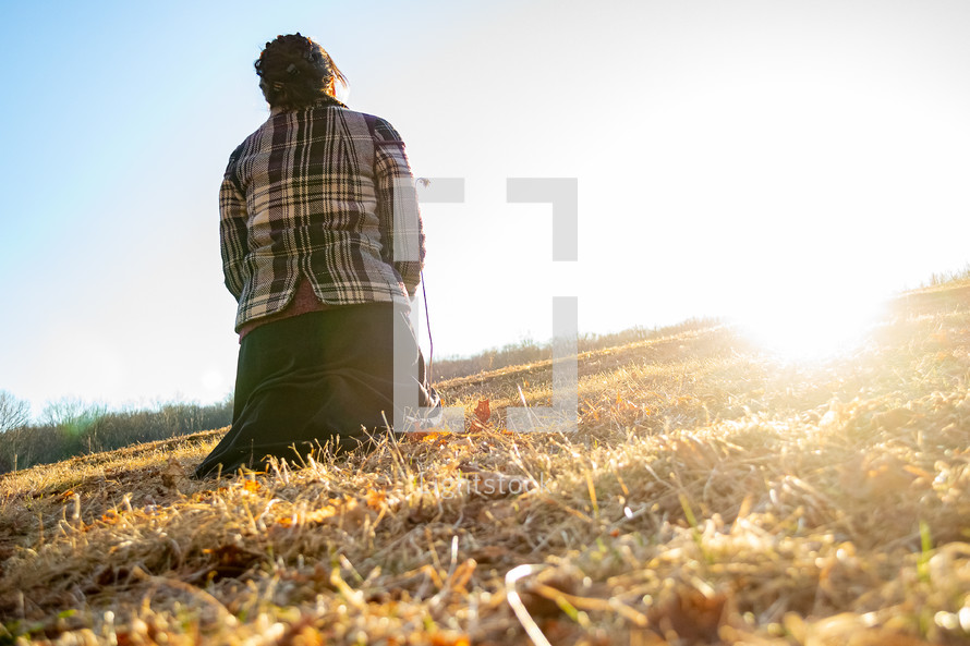 a woman kneeling in a field 