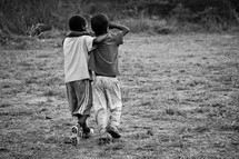 Two young boys with their arms around each other as they walk