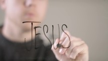 man writing the word Jesus 