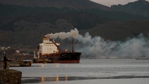 Smoke From Oil Tanker Ship Docked In The Port Of Ushuaia In Tierra del Fuego, Argentina, Patagonia. - wide shot