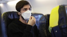 A man putting on respiratory facial, sitting on the board of the plane.