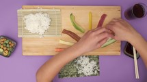Child preparing sushi roll