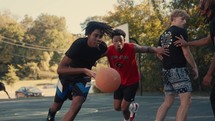 Young men playing basketball on an outdoor court on a sunny day