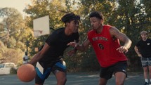 Young men playing basketball on an outdoor court on a sunny day