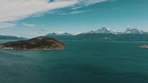 Rugged Island In Beagle Channel Backdropped By Snowy Mountains In Tierra del Fuego, Patagonia, Argentina. wide aerial shot