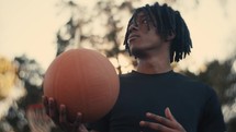 Portrait of a smiling young man playing basketball on a sunny day