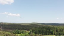 A drone shot of another drone flying over a telecommuncations tower in the forest