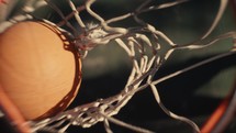 Close up of a basketball being shot on an outdoor basketball court on a sunny day