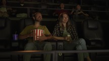 Boyfriend and girlfriend watch comedy film, laughing loudly.