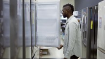 A man inspect the design and quality of fridge before buying in a consumer electronics store.