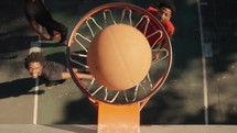 Young men playing basketball on an outdoor court on a sunny day