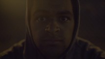 man in a hoodie sitting in the dark and then getting up