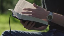 Young man reading his Bible outside on a warm sunny day