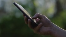 Young man using his phone on a sunny summer day in the forest 