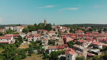 Drone flies over medieval town with church in Istria