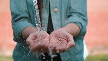 clean water pouring into a woman's hands. 