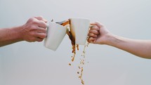 cheers with coffee mugs and coffee spilling over