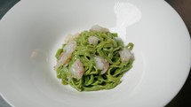 Plating Green Pesto Tagliatelle Pasta With Shrimps Into a First Course Dish