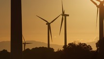 Silhouette of a wind power plant generator at sunset on the mountains