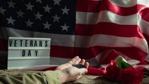 hand of military man holding his dog tag near a USA flag 