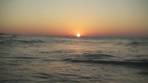tide washing onto a shore at sunrise 