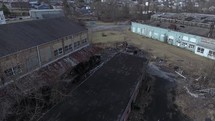 aerial view over an old warehouse and muddy dirt road 