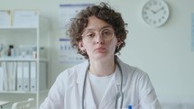 Young Female Doctor Talking on Camera during Online Consultation
