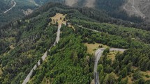 Aerial view of mountain roads surrounded by a lush green forest in Romania.