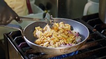 Slow motion of shawarma with onions cooking in a frying pan.