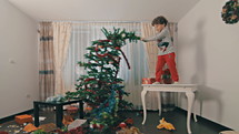 Young boy destroying Christmas tree and gifts.