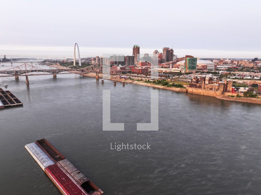 Aerial photo over the Mississippi River looking into a view of downtown Saint Louis, Missouri city on a clear sky day with bridges and skyscrapers.