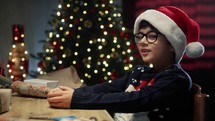Young Kid under Christmas tree making heart with his hands 