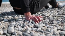 Seated Man With Hand On Stones Near Ocean