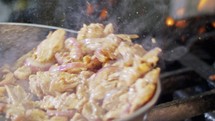 Slow motion of shawarma with onions cooking in a frying pan.