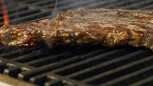 Slow motion of a large beef sirloin steak grilled on a charcoal grill.