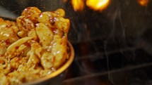 Slow motion of chicken meat fried in a pan with sauce.