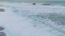 Aerial view capturing wind waves crashing fluidly on a freezing ocean beach