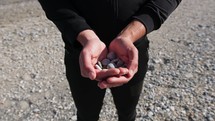 Hands Of A Boy Shows Pebbles On The Beach