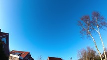 Day to night timelapse over houses and trees on a bright sunny day and starry night