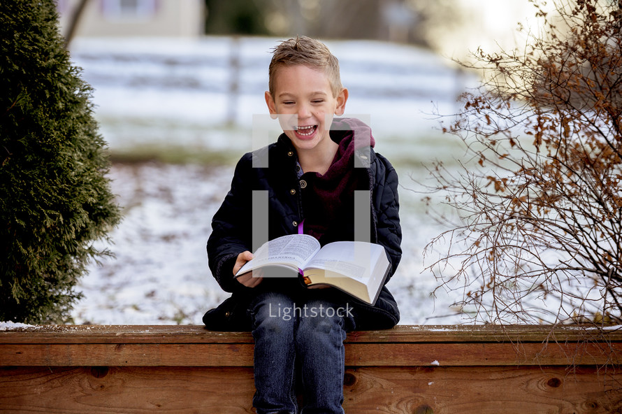child reading a Bible outdoors in snow 