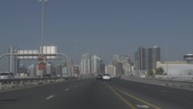 Driving on highway toward Dubai during rush hour traffic in middle eastern city.