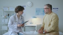 Young Female Doctor Consulting Patient after Health Check-Up in Clinic
