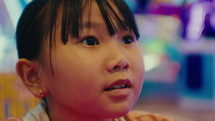 Close-up of the face of a small Asian girl intently playing a game
