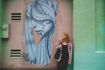 redhead woman posing in front of street art 