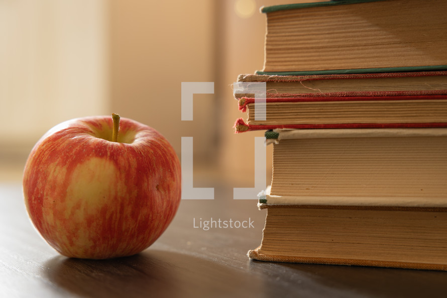 Red apple with stack of vintage books, close up